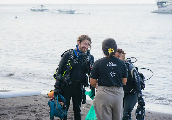 MS Capital team members speaking with divers on the beach after an ocean cleanup